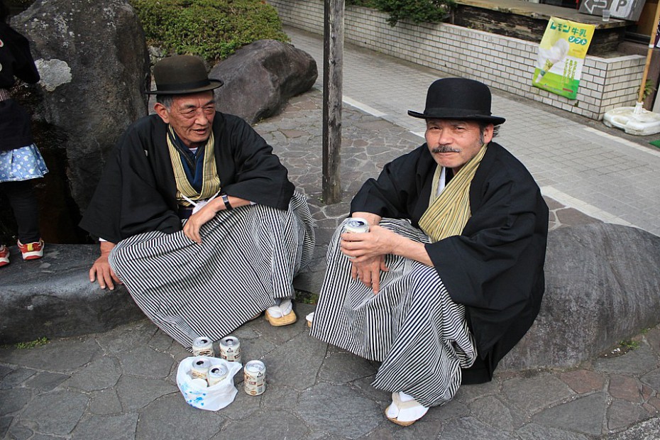 Místní muži v buřinkách, haori a hakamě popíjející pivko